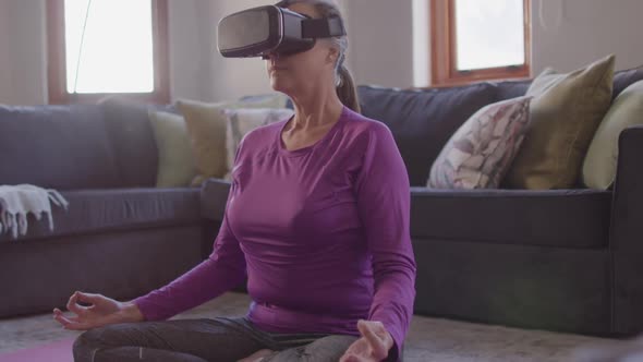 Woman using VR headset while performing yoga at home alt