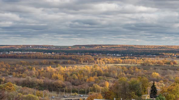 Aerial view of a valley of autumn forests colored by yellow and green with clouds