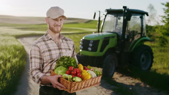 A Farmer is Standing Near a Field and Holding a Basket of Vegetables From the Field alt