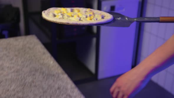 Closeup of the Chef Putting Pizza to Bake in the Oven in the Restaurant Kitchen alt