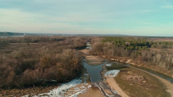 Aerial Drone Footage of Flight Over a Small River in Winter Forest