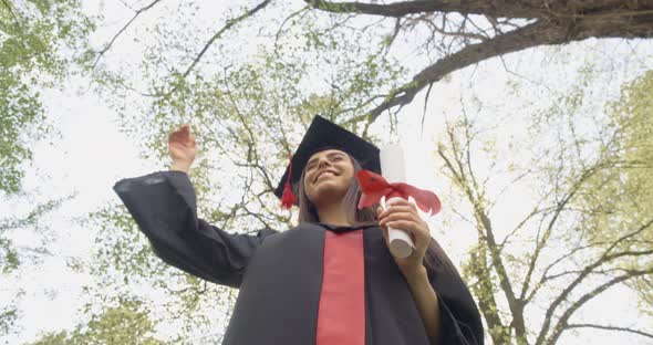 Beautiful Brunette Woman Standing in Park Putting Off Mortarboard Throwing Smiling alt