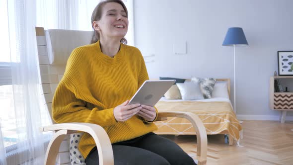 Excited Woman Celebrating Success, while Using Tablet Computer alt