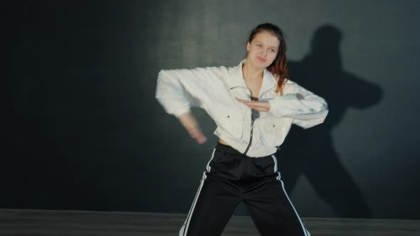 Attractive Teenager in Sports Clothing Dancing in Dark Studio with Illumination alt