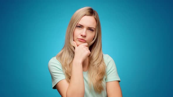 Thoughtful Woman Looking Aside with Pensive Expression Againast Blue Background alt