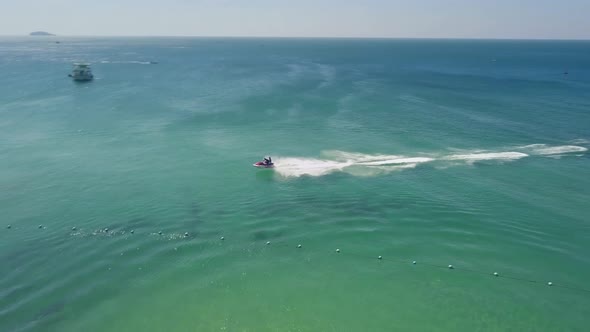 Aerial Tracking Fly Over a Tourist in a Resort Riding a Fast Jetski on Summer alt