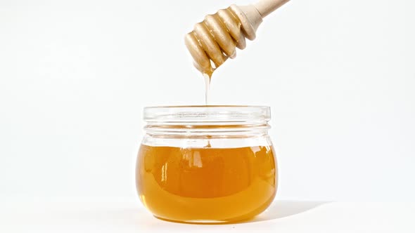 Honey Dripping Pouring From Special Honey Spoon in Glass Bowl alt