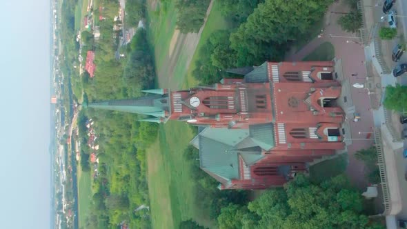 Church in Small City Among Pastures. Drone Footage. Red Church Is Roman Catholic Church. alt