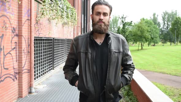 portrait young beautiful bearded man outdoor looking camera hands in pocket alt