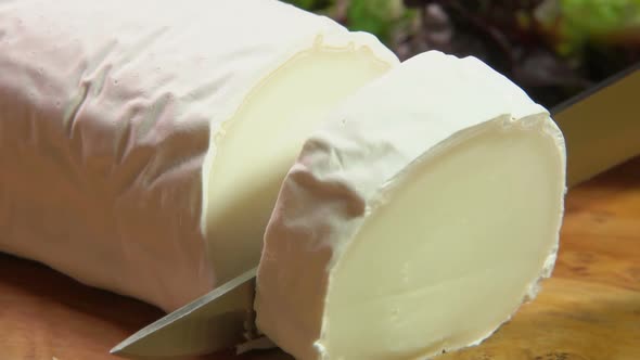 Piece of Goat Cheese with Gray Mold Is Cut with a Knife alt