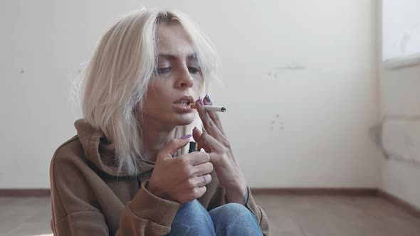 Young Depressed Girl Smokes a Cigar Sitting on the Floor Indoor 