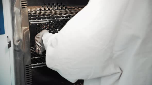 Nurse Takes Metal Pan with Sterilized Surgical Tools Out of Autoclave Sterilizer alt
