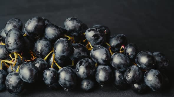 A Girl With a Beautiful Manicure Picks a Berry From a Bunch of Grapes alt