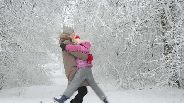Happy mom plays with her daughter in a beautiful winter park.