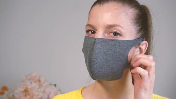 Woman Looking in Camera and Taking Off Face Protective Mask