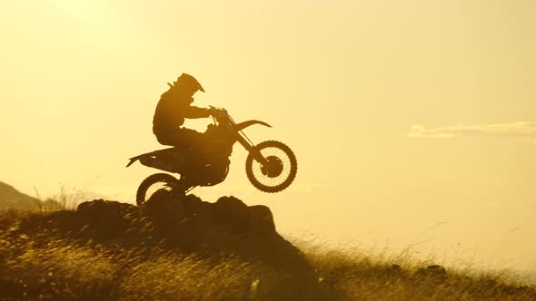 Silhouette of Extreme Motocross Biker Jumping Motor Bike on Sunrise Background