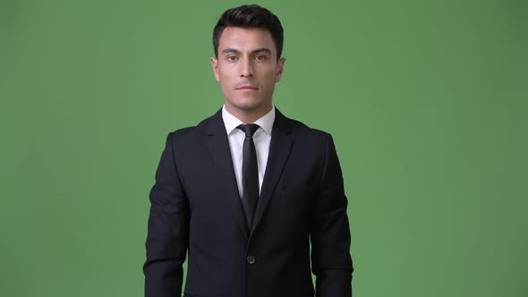 Young Handsome Hispanic Businessman Against Green Background alt