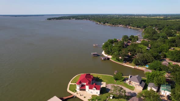 Aerial footage of Cedar Creek Lake in Texas. Drone flies over several houses on the shore. alt