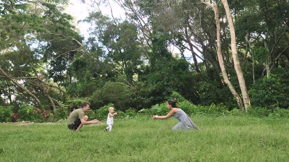 Young Parents Teaching and Encouraging Their Baby to Walk in the Park