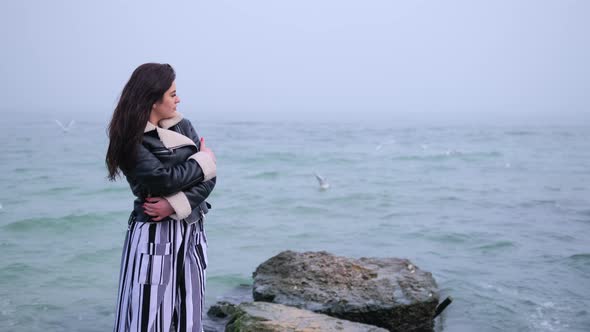 Woman at the Seaside Standing on Beach Looking Out Over Ocean Watching Seagulls alt
