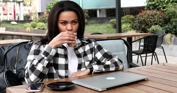 Young positive black female in outdoor cafe start working day remotely, opening laptop.