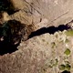 Drone facing straight down while flying over rugged rocky coast line while water laps at the base of - VideoHive Item for Sale