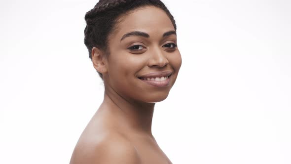 Back View of Young Nude African American Lady Turning To Camera and Smiling White Studio Background alt