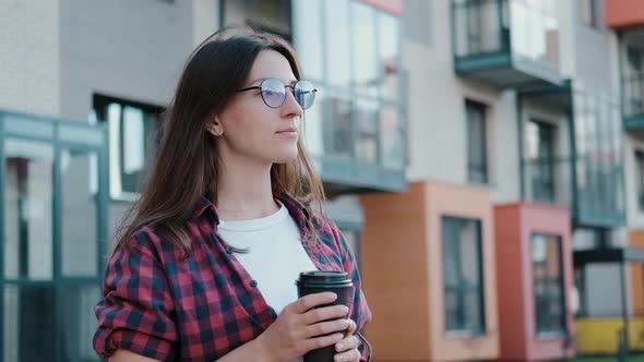 Young Attractive European Girl with Coffee While Walking Looks Around