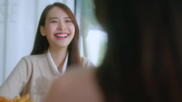 attractive asian female talking good positive conversation to friends with smiling laugh