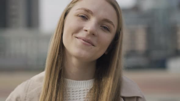 Close-up Face of Charming Young Caucasian Woman with Grey Eyes Looking at Camera and Smiling alt