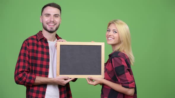 Young Happy Couple Holding Blackboard Together