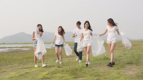 Young multiethnical volunteers help to keep nature clean up, smile with white garbage.
