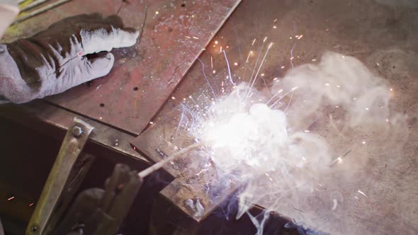 Detail of hands of Caucasian male factory worker at a factory standing in a workbench, welding alt