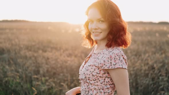 Close Up Portrait of Young Woman Smiling with Red Hair Blowing in Wind Looking at Camera alt