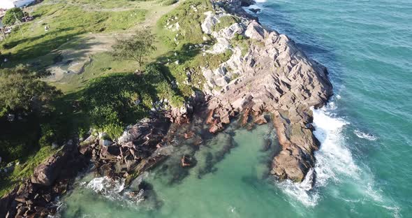 Aerial footage of the the beautifu rocks and sunny beach of Armação in Florianópolis, Brazil. alt