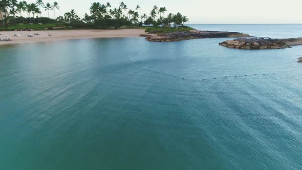 Aerial view scenic bay water surrounded by Rocky pontoon, palm trees coastline alt