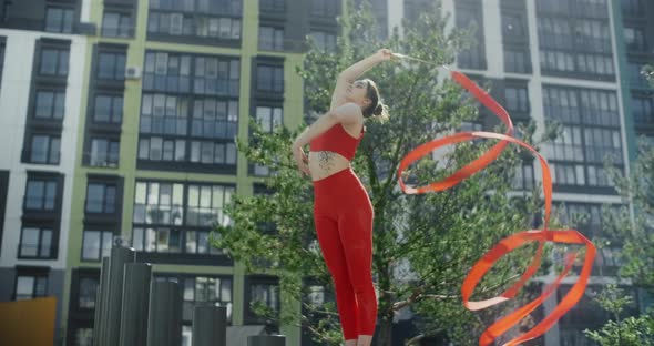 Young Woman in Red Performs Callisthenics with Ribbon in the Libing Apartment Yard, Gymnast Does alt