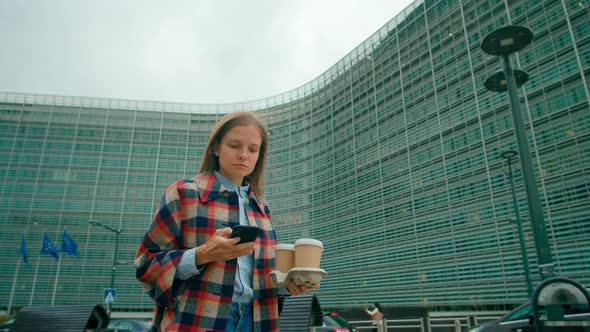 Official Lady Walks with Coffee By EU Modern Office in Brussels Using Phone App