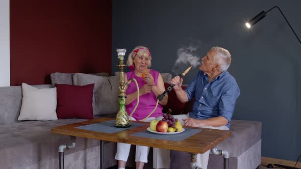Stylish Senior Couple Enjoy Smoking Hookah, Eating Fruits at Home, Celebrating, Having Fun Together alt