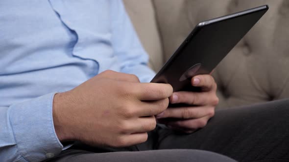 Close Up Hands Businessman Uses Tablet Sitting on Couch at Home Office alt