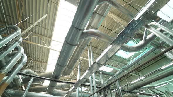 Pipes of the ventilation system are located on the ceiling of plant with the production of parquet. alt
