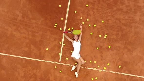 Girl relaxing on tennis court with a lot of balls and racket after hard tennis trainingg outdoor alt