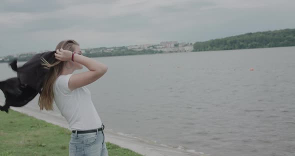 Happy Girl Tosses the Sweater on Shoulders During Seaside Walk in Windy Morning alt