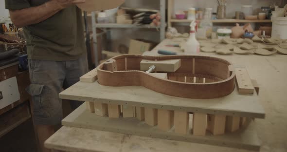 Luthier taps on a guitar wooden part