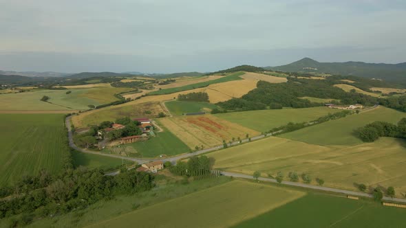Aerial images of Tuscany in Italy cultivated fields summer, Small farm with mountains in the backgro alt