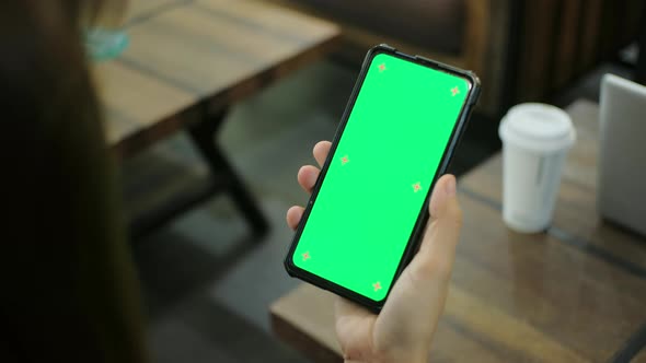 Woman holding chroma key green screen smartphone watching content