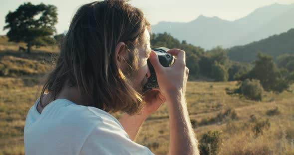 Portrait of Male Travel Photographer Make a Shot on Digital Camera on Mountain alt