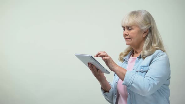 Thoughtful Elderly Lady Scrolling Screen on Tablet, Online Banking Application alt
