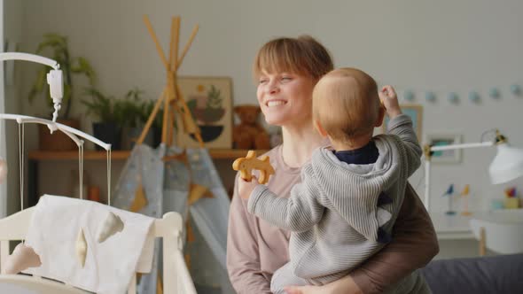 Cheerful Mother Bonding with Baby in Kids Room alt