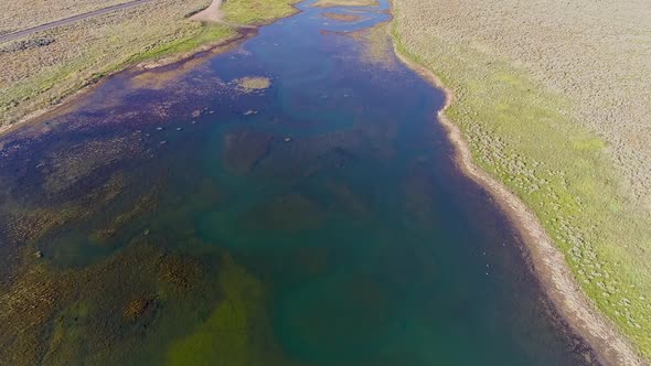 Aerial view flying over river inlet as it flows into lake alt